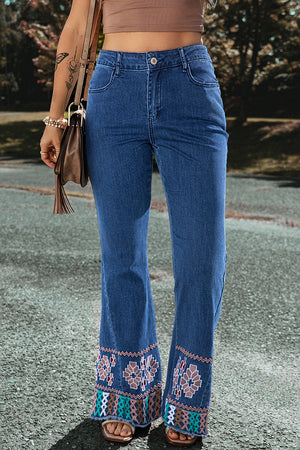 Embroidered hem flare jeans in medium blue denim with a boho pattern on the flared leg openings.