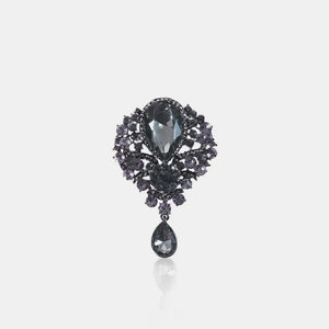 Black teardrop embellished brooch with faceted stones and dangling charm.
