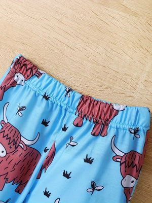 Baby pajama set with blue fabric and a cute Highland cow print.