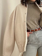 Beige boucle cocoon jacket with snap closure and patch pockets.
