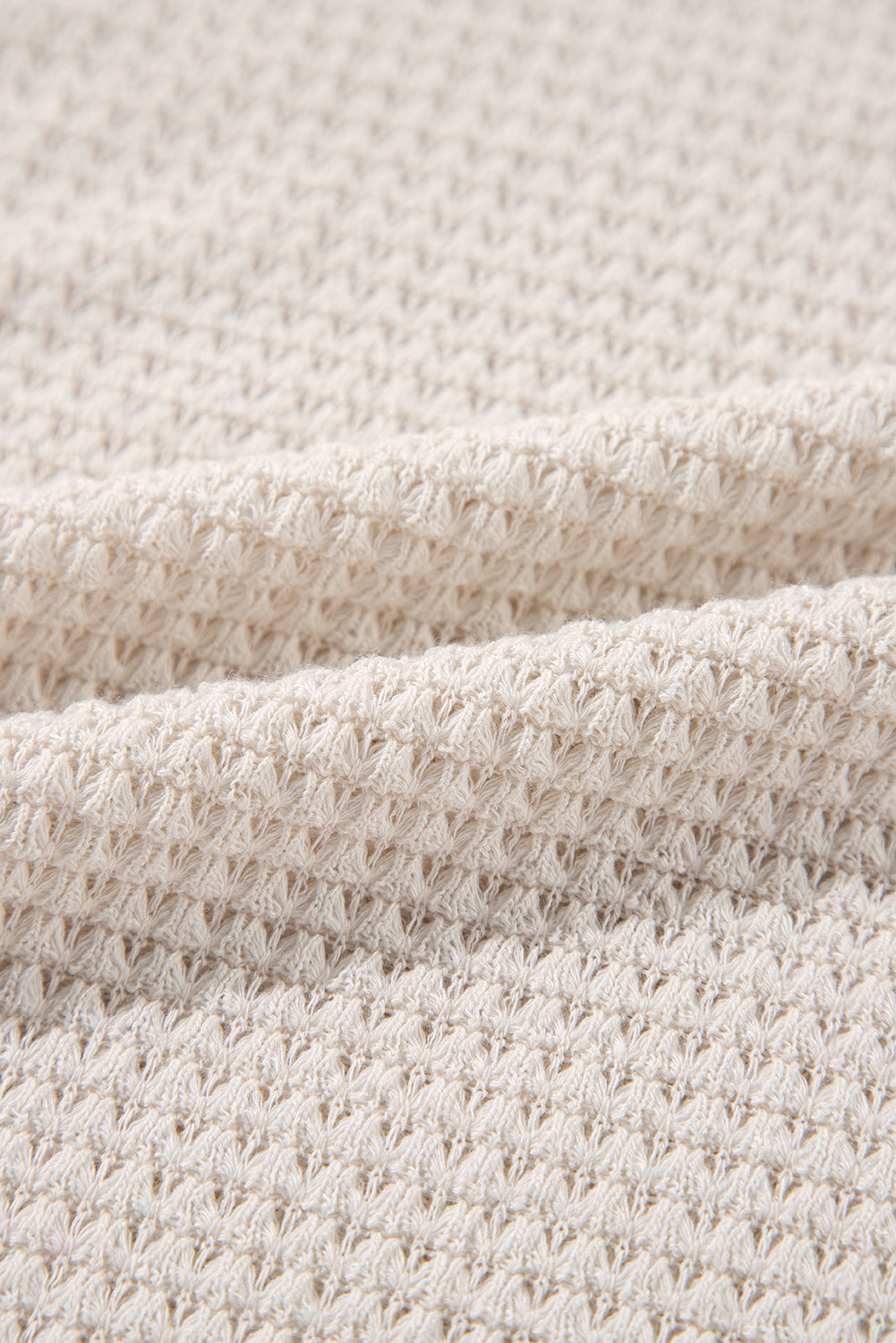 Beige waffle knit V-neck top with slit hem detail.