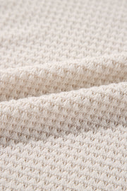 Beige waffle knit V-neck top with slit hem detail.