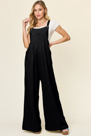 Black pleated bib wide leg jumpsuit with adjustable straps and pockets