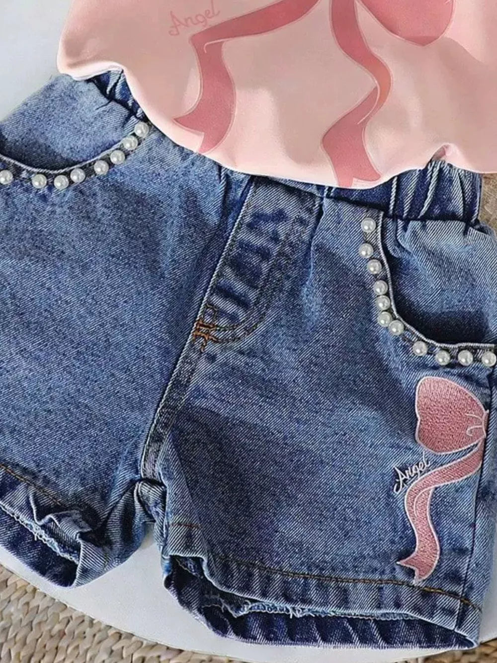 Blush pink tee and blue denim shorts set with pearl trim and bowknot embroidery.