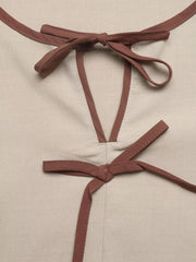 Charming V-neck blouse in beige with brown trim and bow details at neckline and waist.