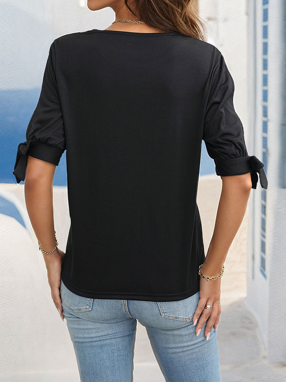 Black blouse with split sleeves featuring bow details at the cuffs.