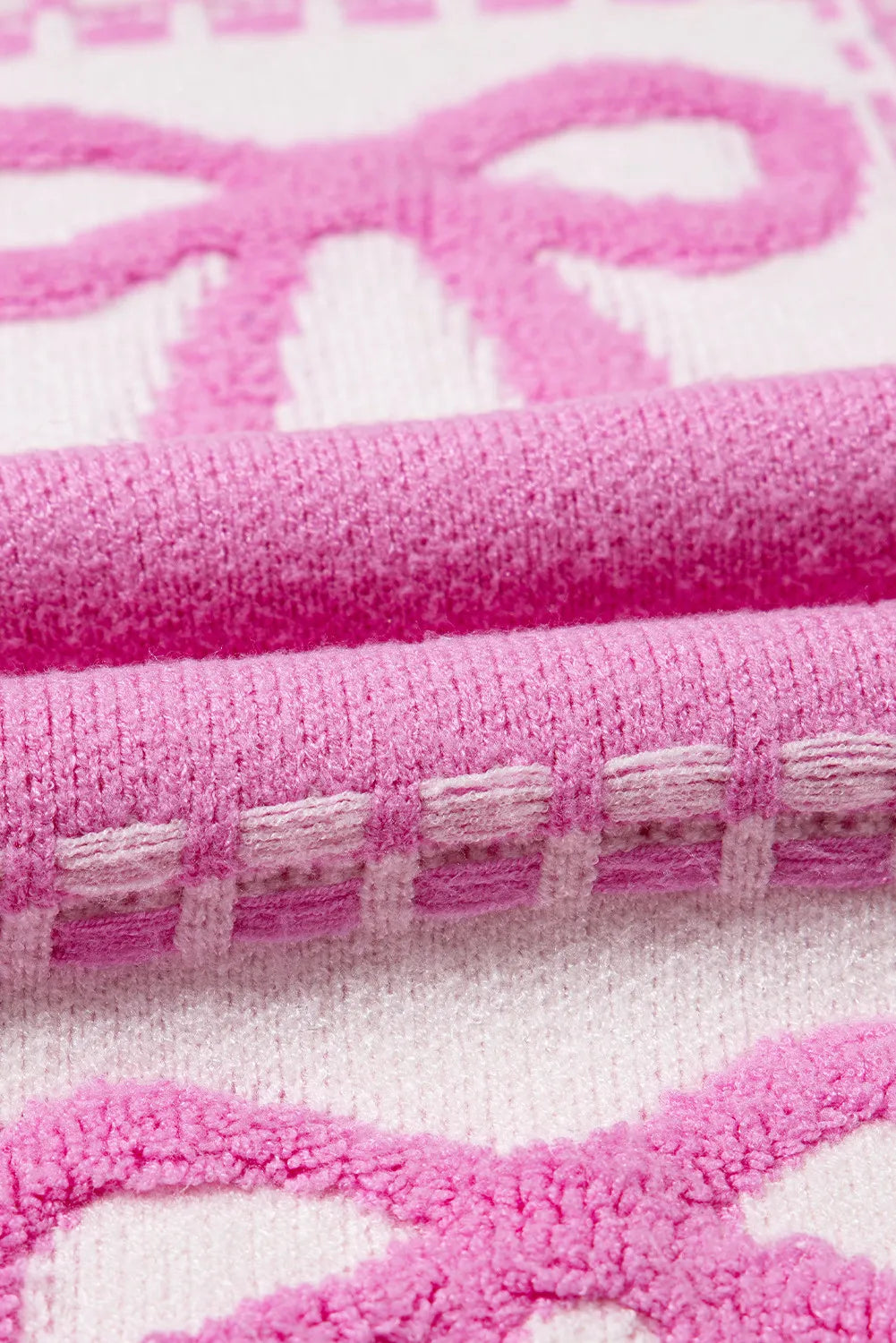 Fuchsia pink and white jacquard knit sweater with bow pattern and textured details.