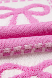 Fuchsia pink and white jacquard knit sweater with bow pattern and textured details.