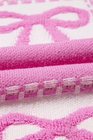 Fuchsia pink and white jacquard knit sweater with bow pattern and textured details.