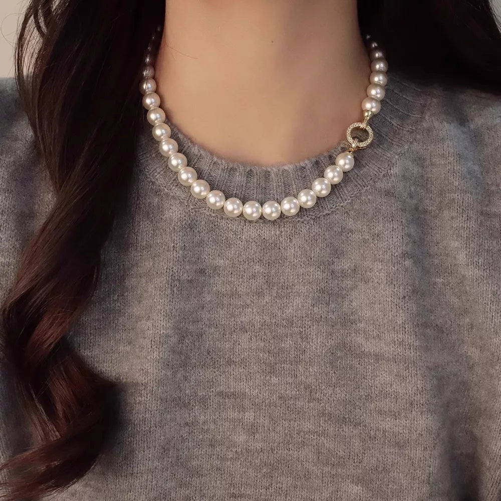 Lustrous pearl choker necklace with ornate gold clasp detail.
