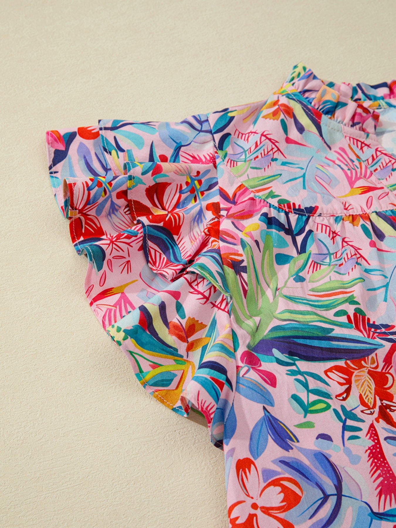 Tropical floral print cotton blouse with ruffled short sleeves and mock neck.