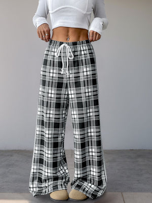 Black plaid wide-leg track pants with white side stripe and drawstring waist.