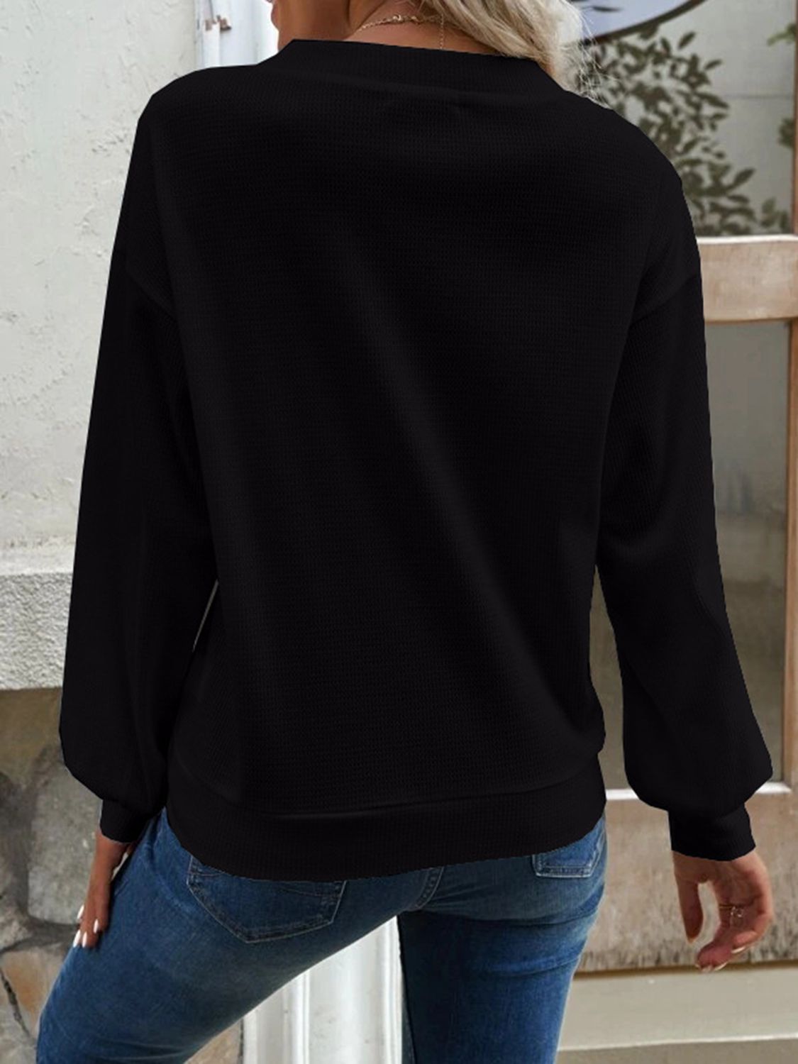 Black waffle knit button-down cardigan with long sleeves and a crew neck.