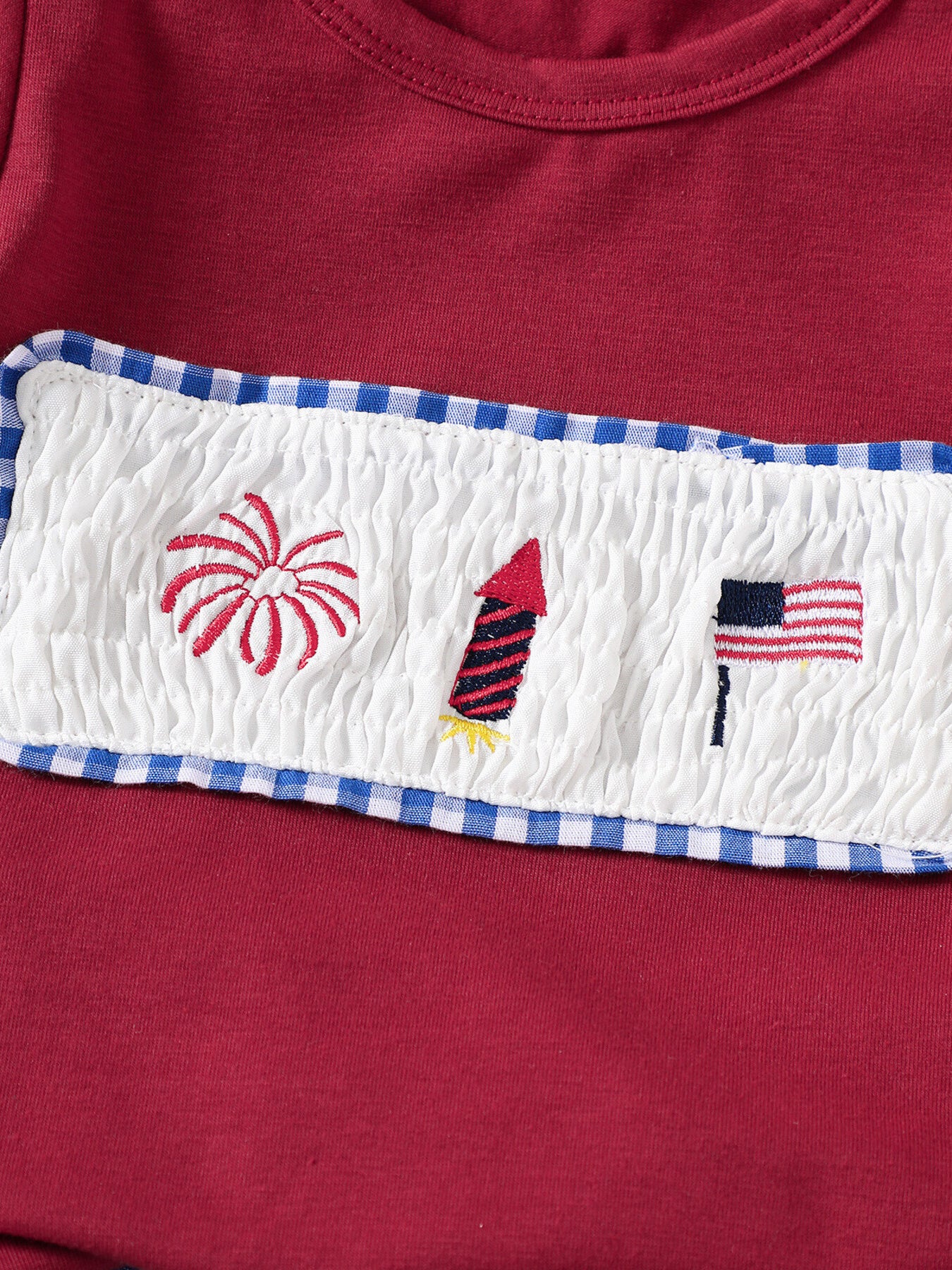 Red baby set with smocked panel embroidery of fireworks, rocket, and American flag.