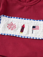 Red baby set with smocked panel embroidery of fireworks, rocket, and American flag.