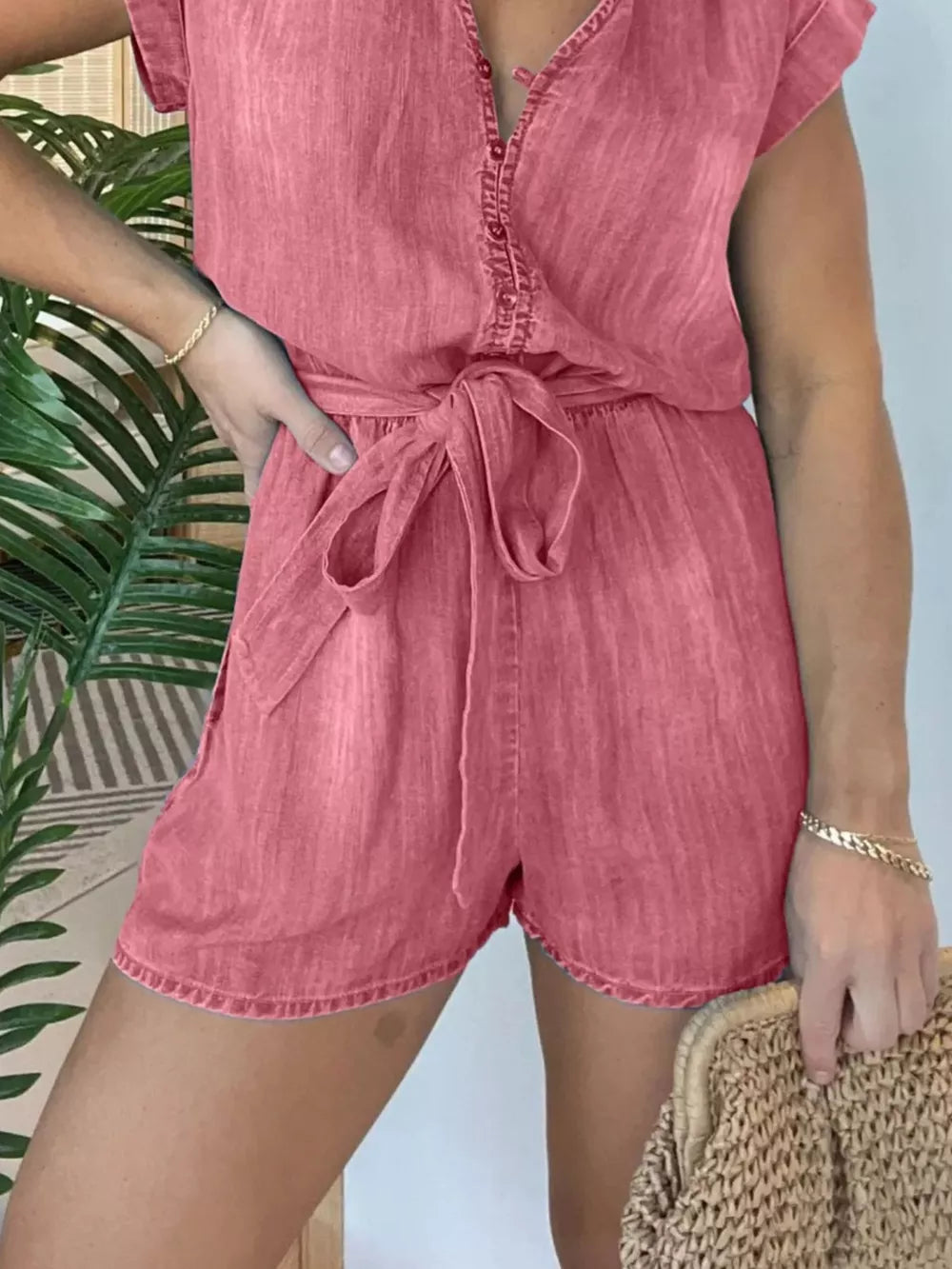 Coral tie-waist romper with button-down front and short sleeves.