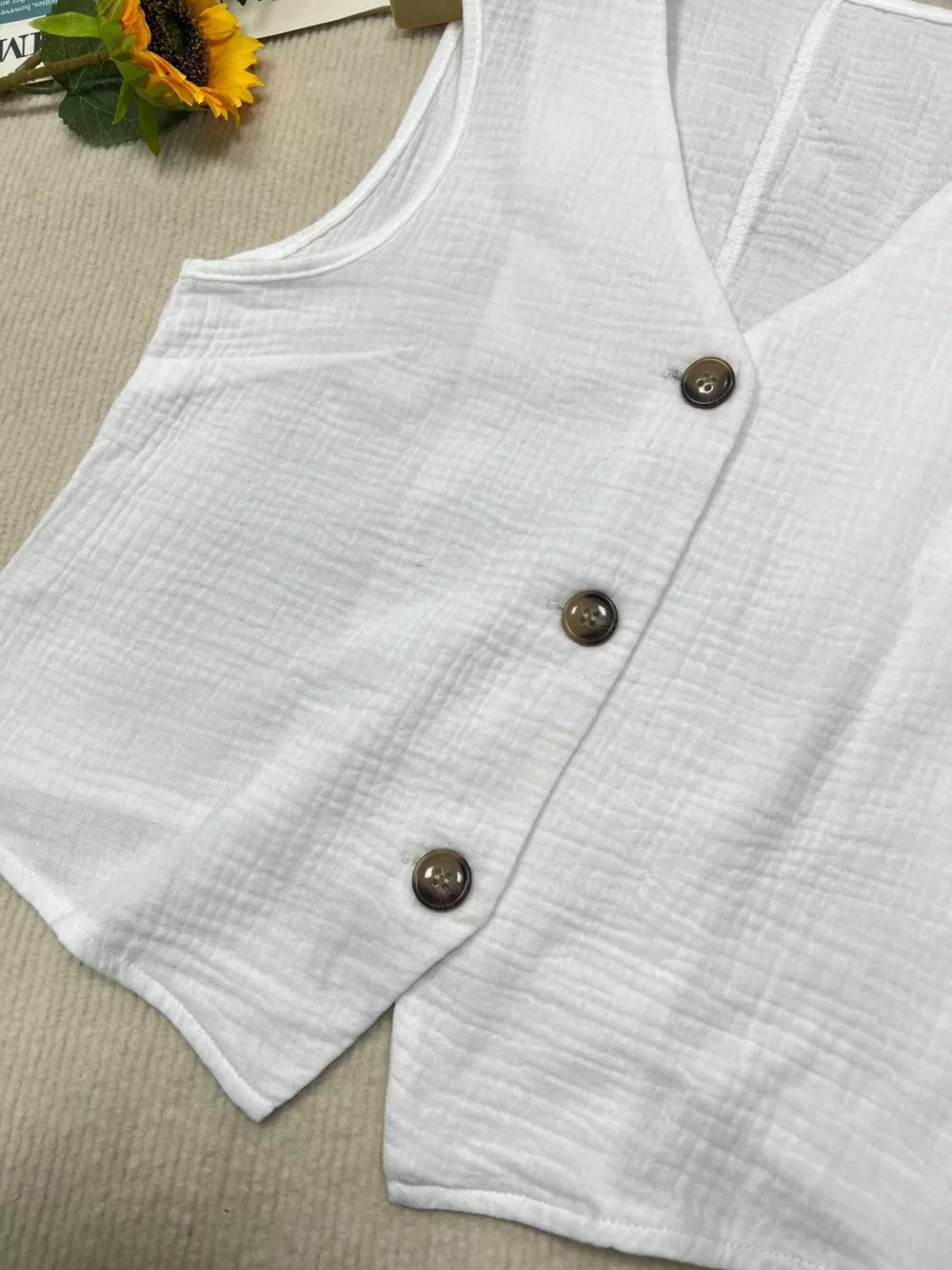 White textured vest with tortoiseshell buttons and V-neck