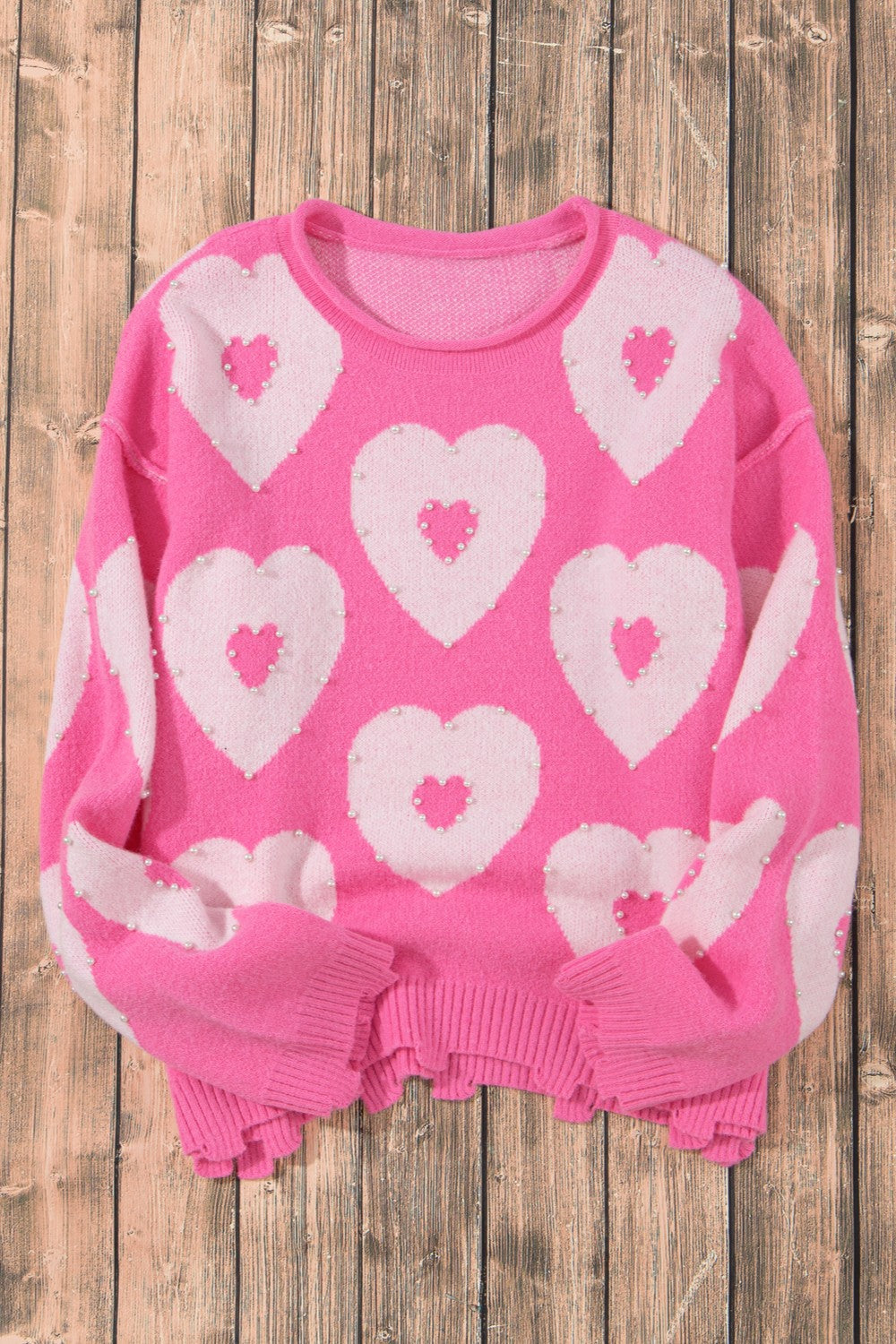 Fuchsia pink knit sweater with pearl-embellished heart motif and crew neck.