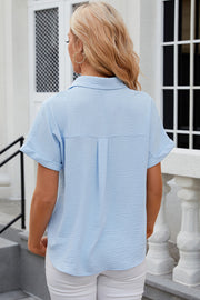 Light blue textured short sleeve collared shirt with cuffed sleeves and back pleat detail.