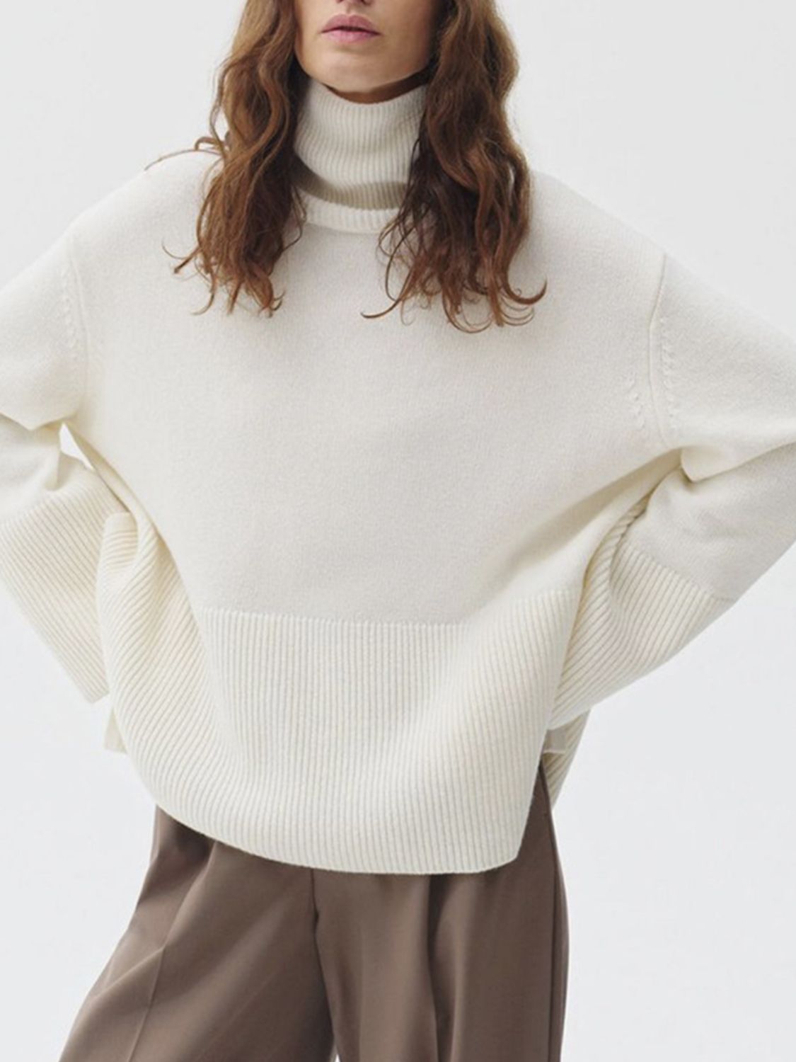 Ivory ribbed turtleneck sweater with flared sleeves and a relaxed fit.