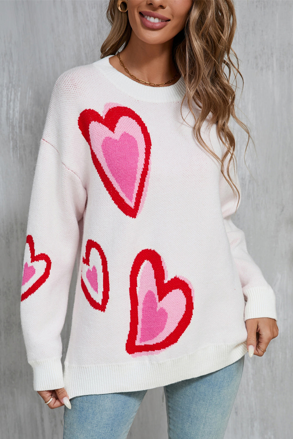 White acrylic sweater with intarsia heart motif in red and pink.