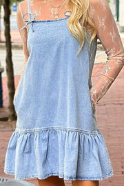 Light blue denim sundress with ruffled hem and bow straps, worn with lace sleeves.
