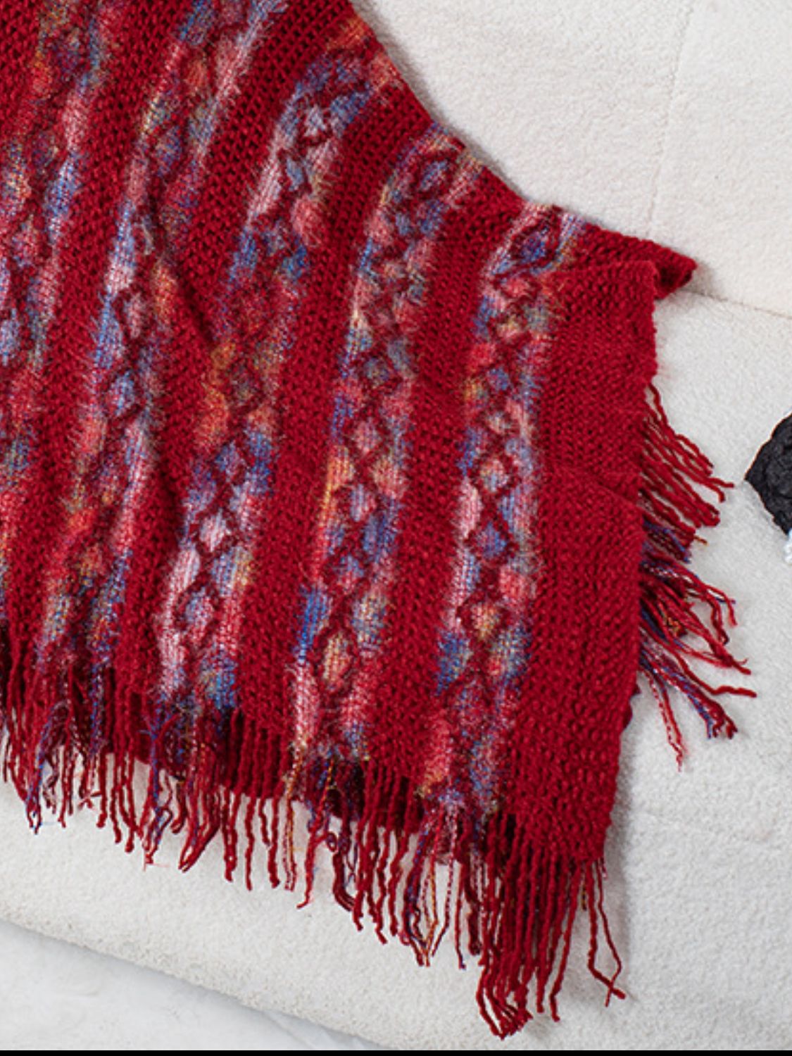 Textured knit cape in terracotta with diamond pattern and fringe detail.