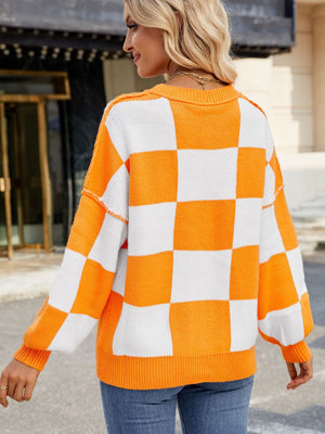 Checkerboard knit sweater in tangerine and white with balloon sleeves and ribbed cuffs.