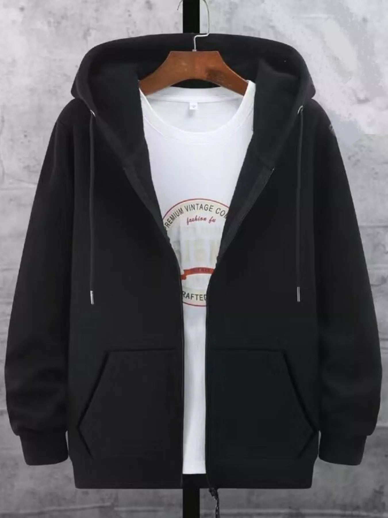 Black fleece-lined zip-up hoodie with front pockets and drawstring hood, worn over a white graphic tee.