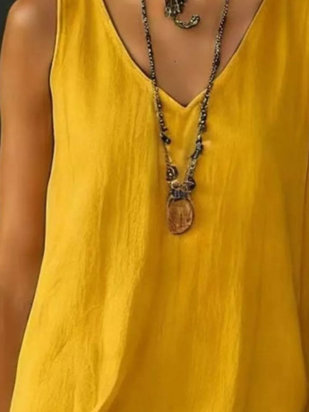 Yellow tiered ruffled hem V-neck dress with a textured fabric and layered necklace.