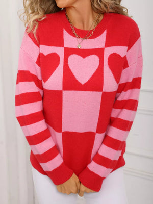Red and blush pink checkerboard knit sweater with heart details and striped sleeves.