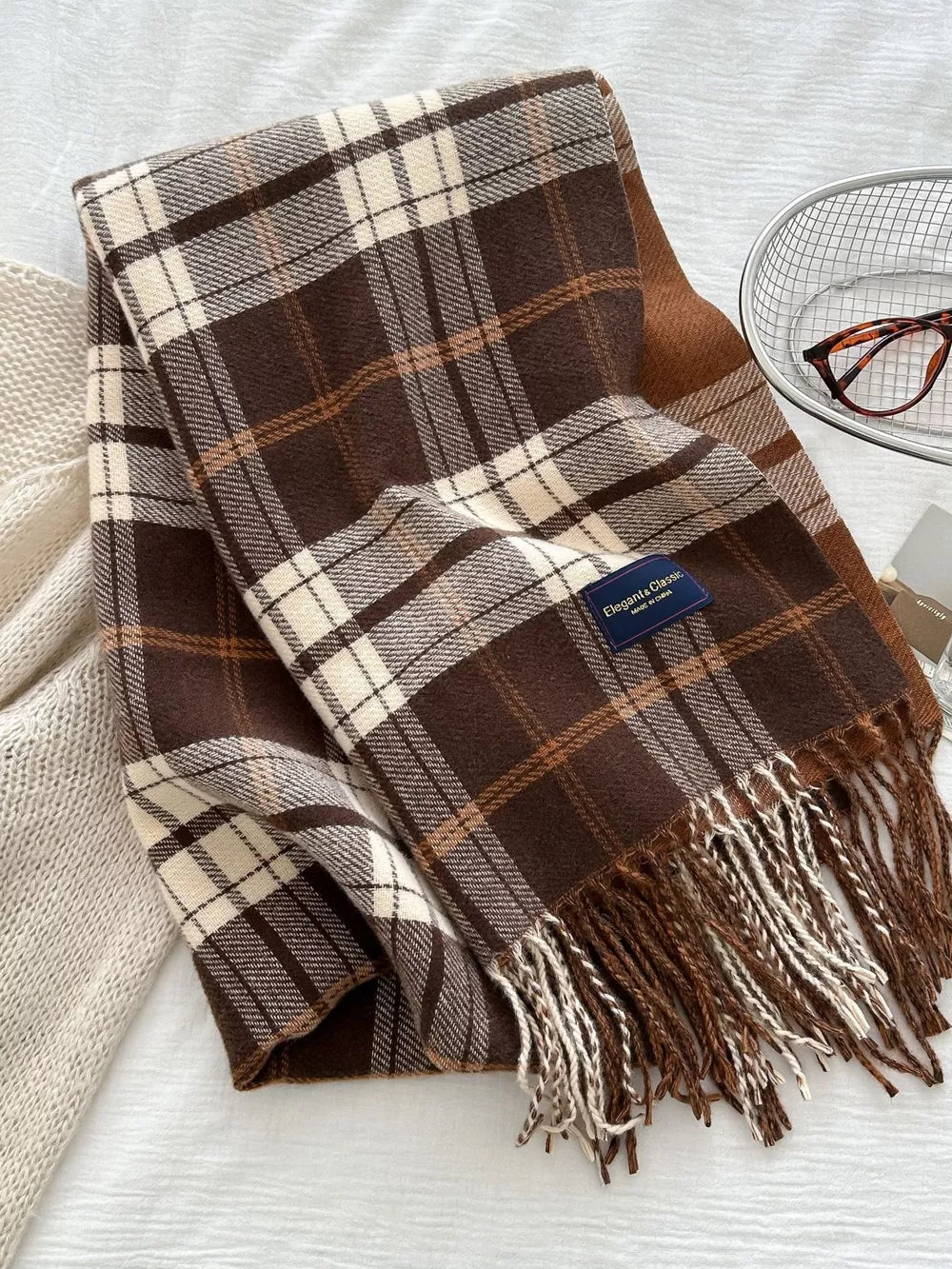 Tan plaid fringe scarf with brown and cream details and a blue label.