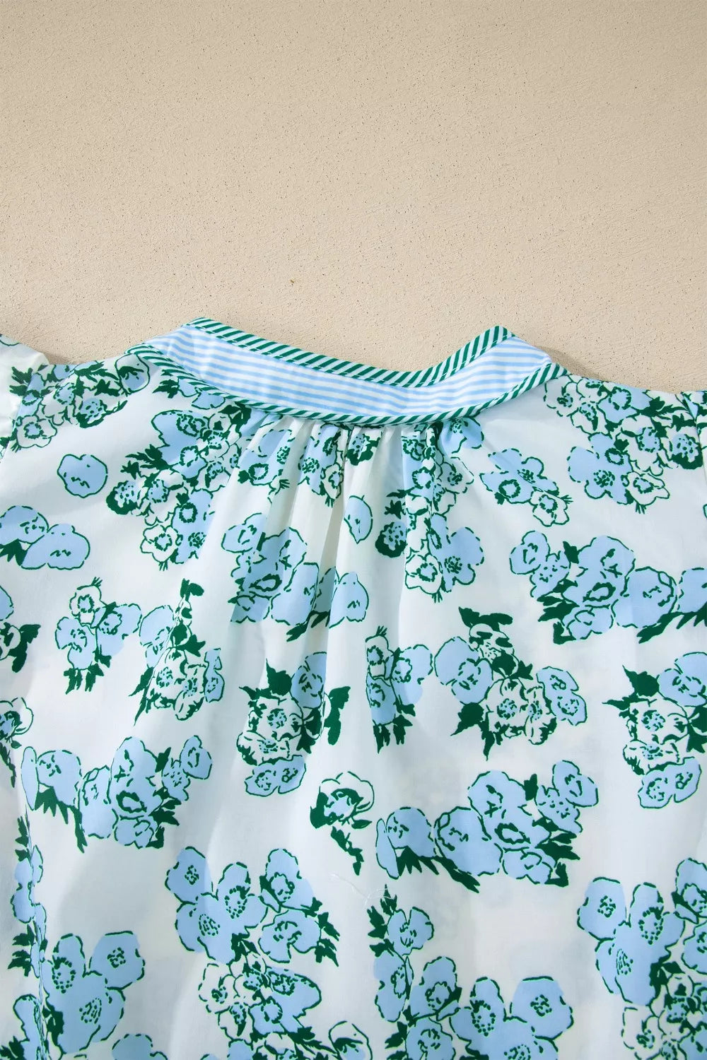 Floral print blouse with flutter sleeves and a striped collar.