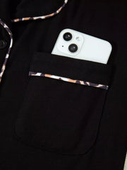 Black pajama top with leopard trim pocket and collar detail, phone shown.