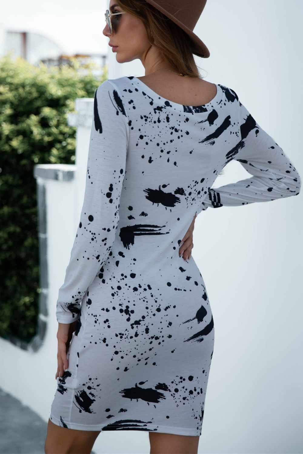 White long sleeve bodycon dress with black splatter print and scoop neck.