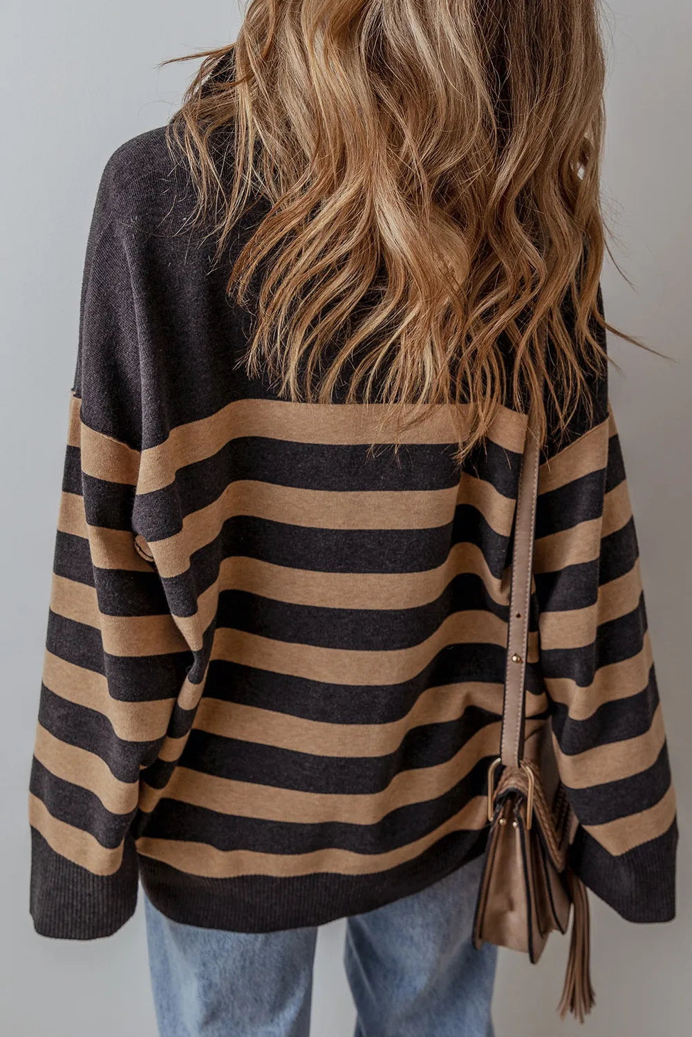 Oversized knit pullover with horizontal stripes and half-zip neckline.
