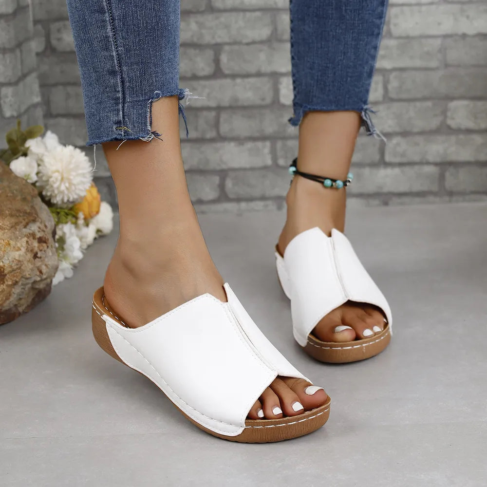 White vegan leather asymmetrical slides with peep toe and contoured sole.