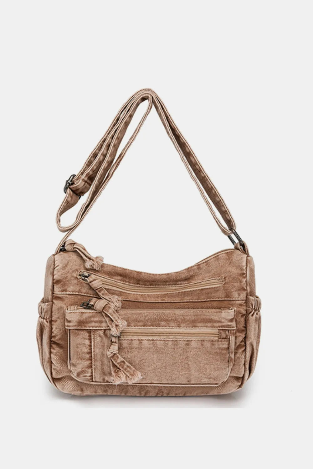 Acid wash denim crossbody bag in camel with multiple zippered pockets and tassel detail.