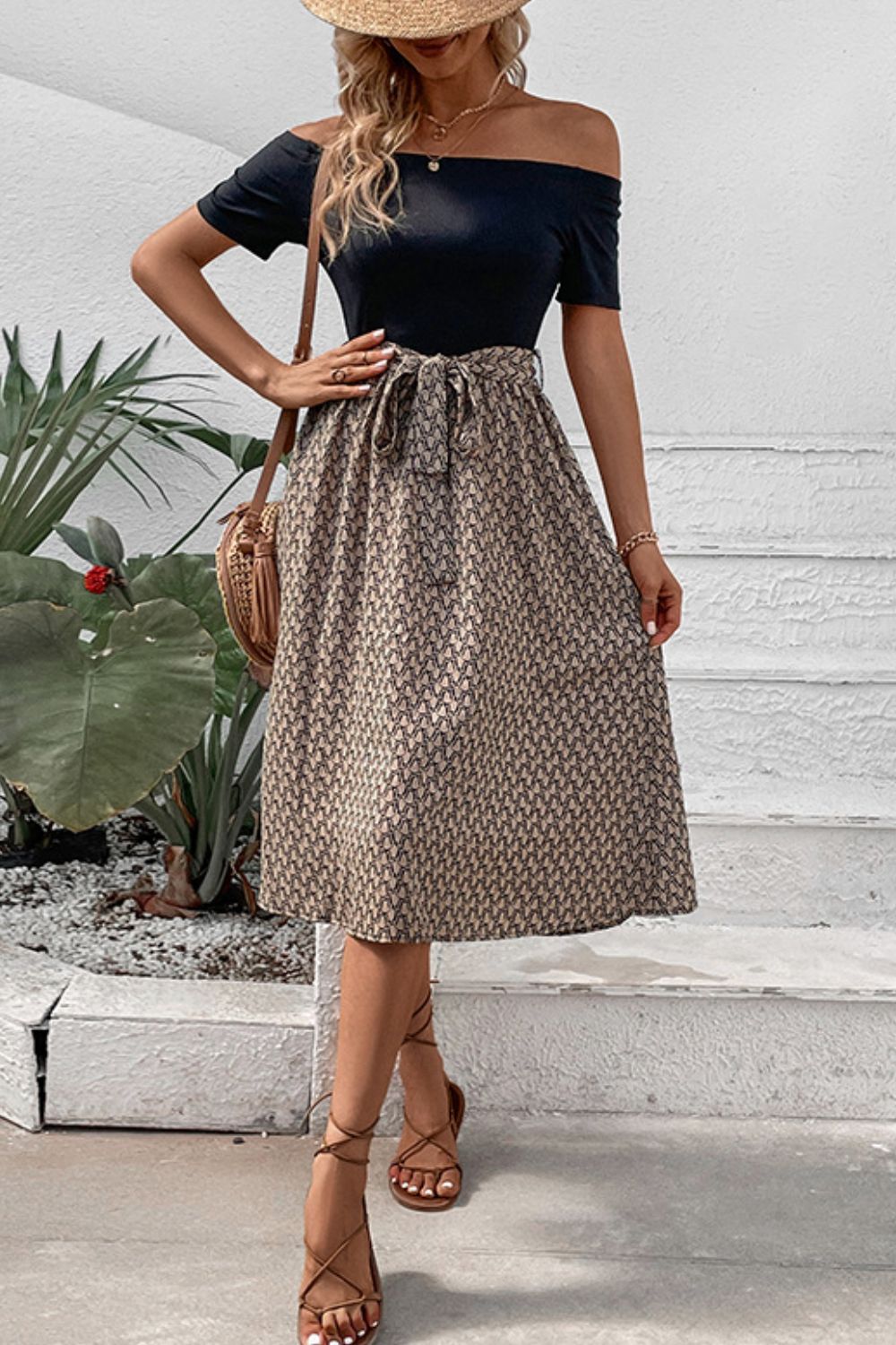Black off-shoulder midi dress with a patterned A-line skirt and tie waist.
