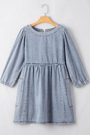 Gathered waist denim mini dress in medium blue with balloon sleeves and pockets.
