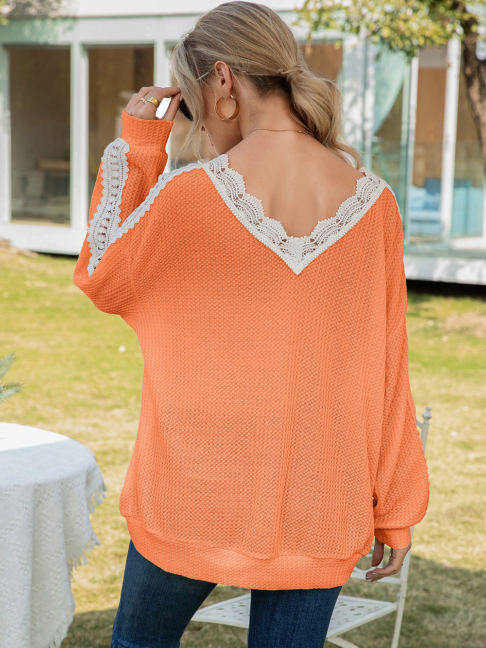 Orange waffle knit top with V-neck lace trim and long sleeves.