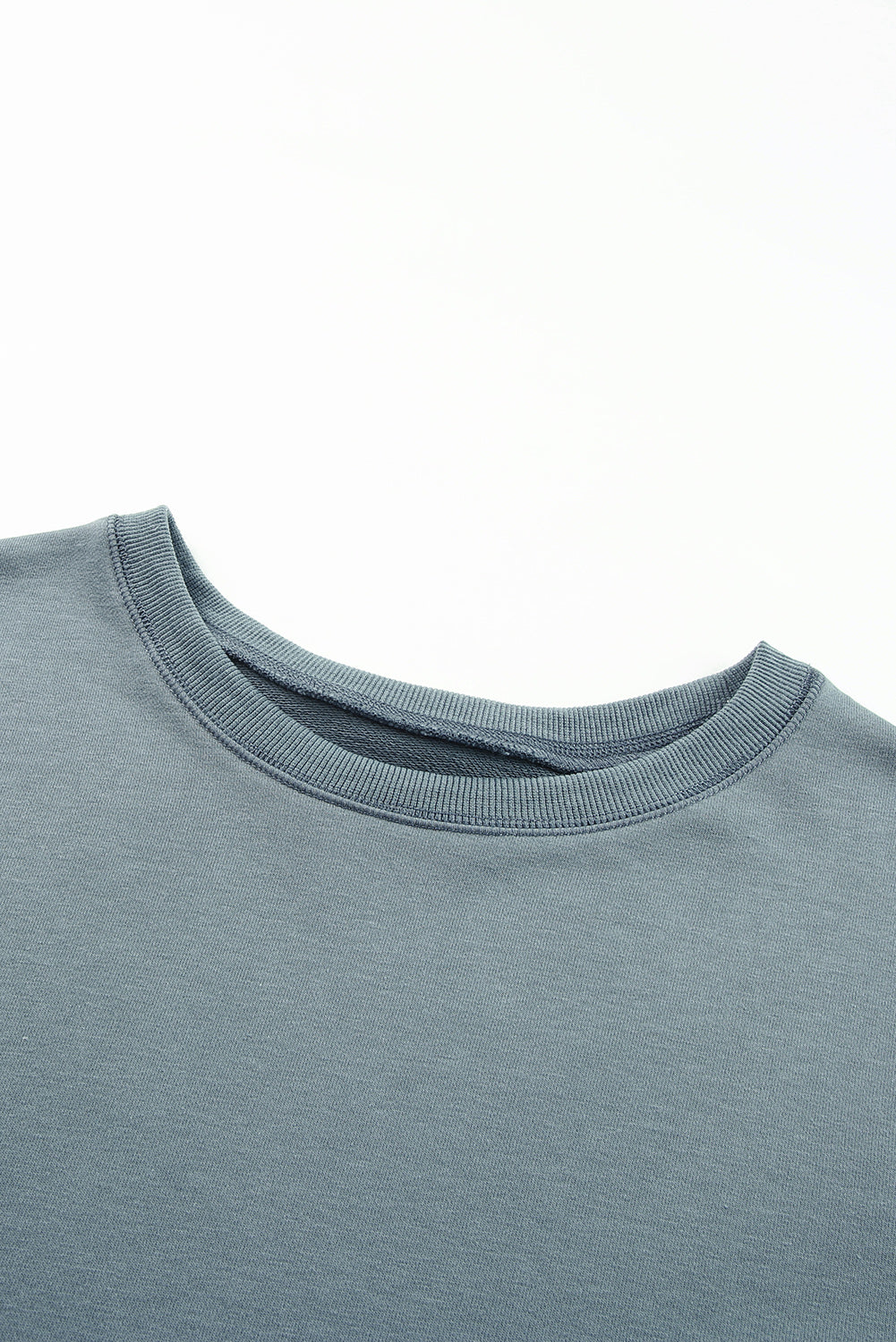 Dull blue crewneck sweatshirt with ribbed collar and cuffs, showing asymmetric hem detail.