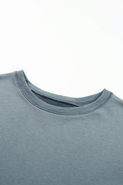 Dull blue crewneck sweatshirt with ribbed collar and cuffs, showing asymmetric hem detail.