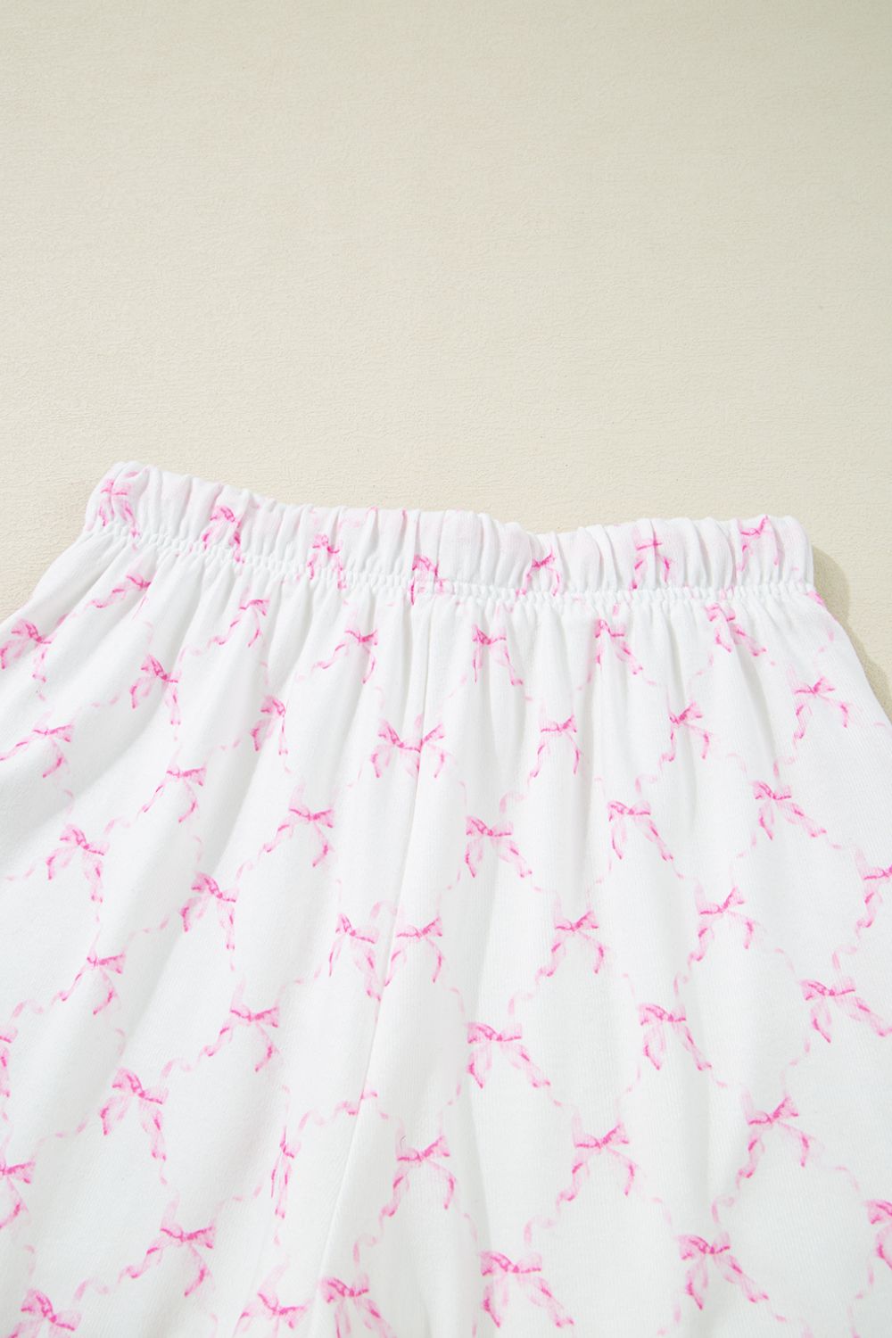Pink bow print lounge set with elastic waistband and scalloped edges.