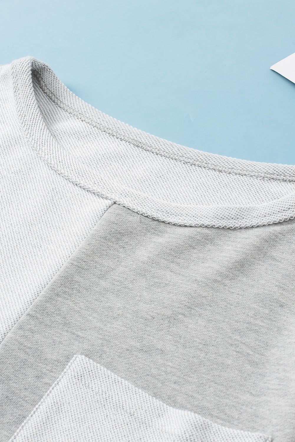 Colorblock sweatshirt in light gray with crew neck and pocket detail.