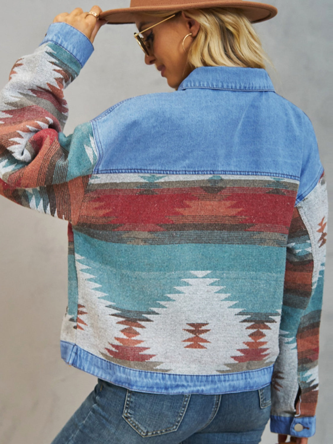 Southwestern denim jacket in dusty blue with colorful geometric pattern on sleeves and back panels.