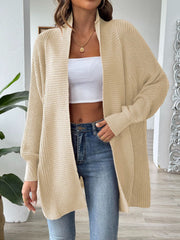 Tan ribbed knit cocoon cardigan with open front and long sleeves, styled with a white crop top and jeans.