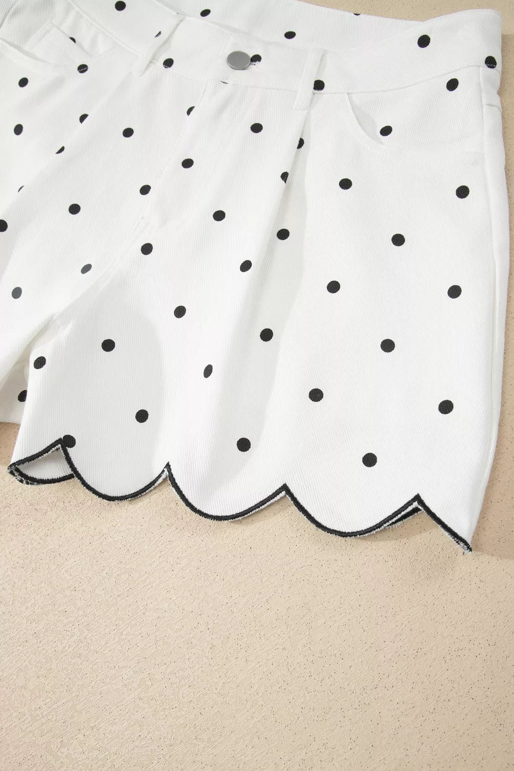 White chino shorts with black polka dots and a scalloped hem detail.