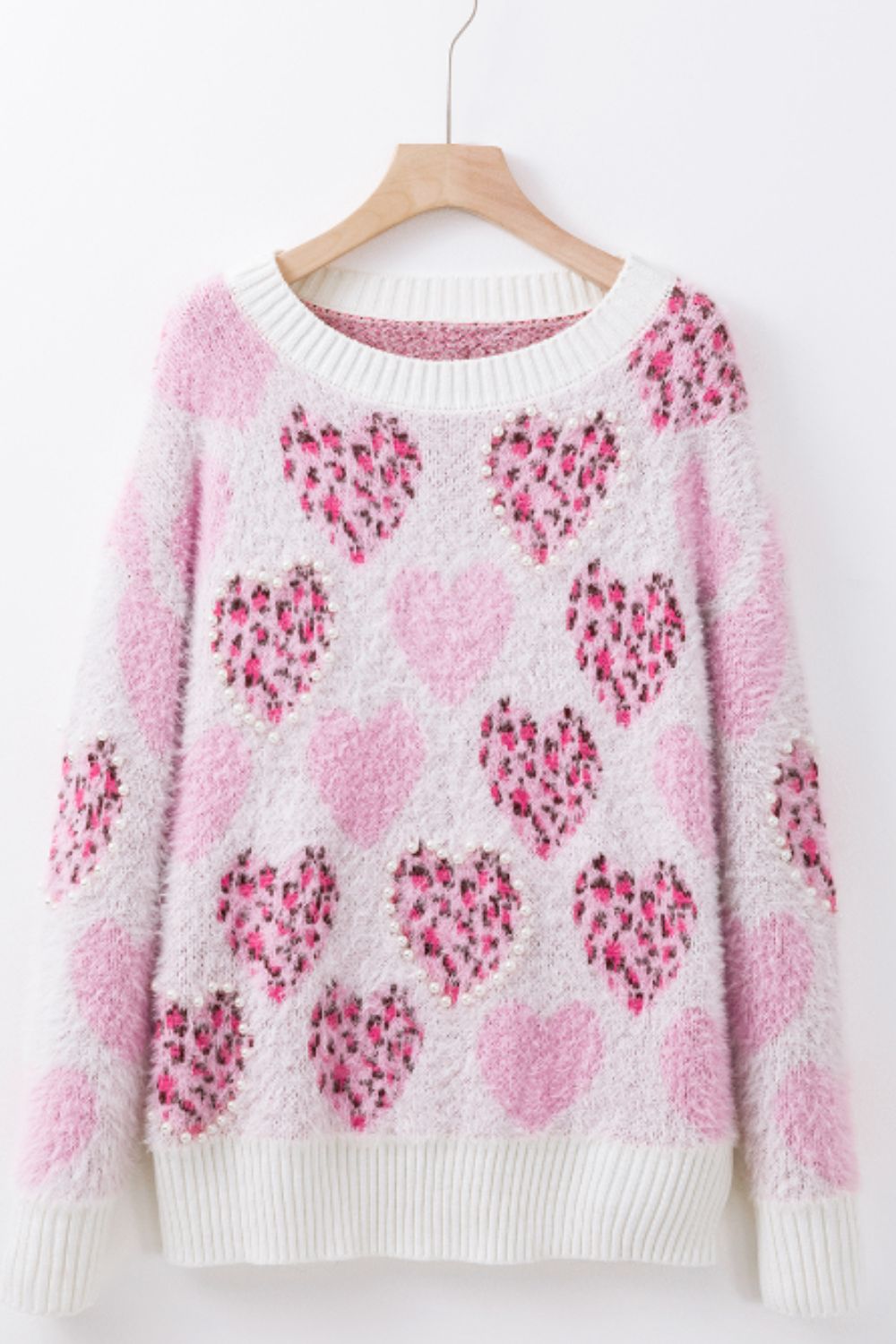 Fuzzy knit sweater in blush pink with allover heart pattern and pearl embellishments.