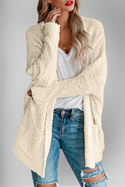 Cream popcorn knit open cardigan with textured detail and pockets.